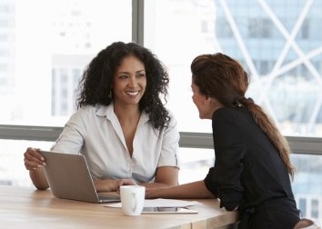 Two women sat at a desk in a meeting 